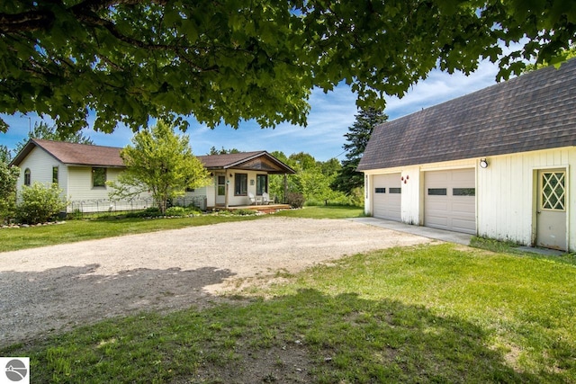 view of front of property with a front yard, an outdoor structure, driveway, and a shingled roof