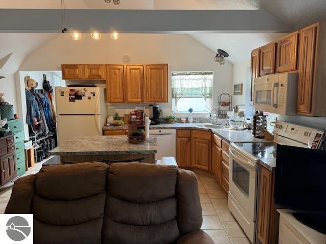 kitchen featuring a center island, lofted ceiling, light tile patterned floors, white appliances, and a sink