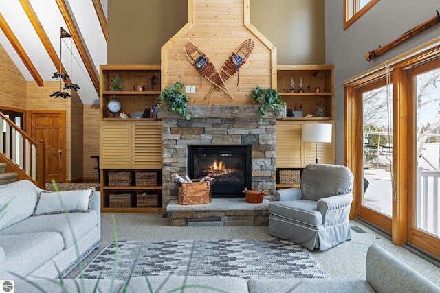 living room with stairway, wood walls, a fireplace, and high vaulted ceiling