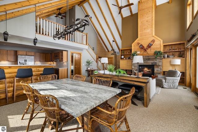 dining space with a stone fireplace, light colored carpet, high vaulted ceiling, and ceiling fan