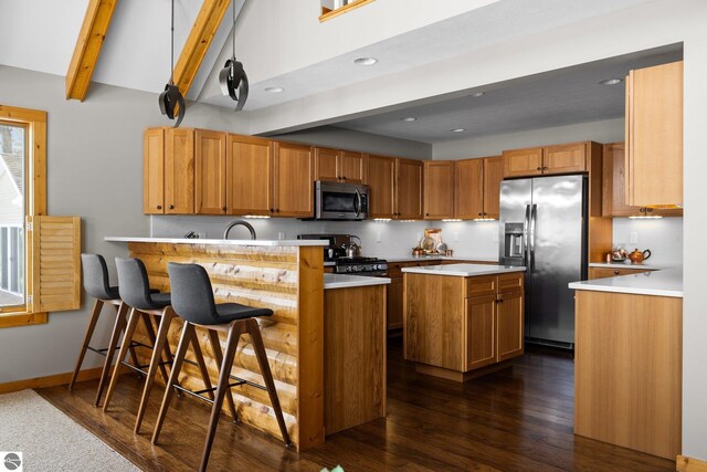 kitchen with light countertops, a kitchen breakfast bar, appliances with stainless steel finishes, a peninsula, and dark wood-style floors