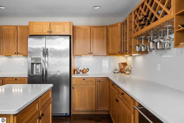 kitchen with glass insert cabinets, stainless steel fridge with ice dispenser, light countertops, dark wood-style floors, and brown cabinetry