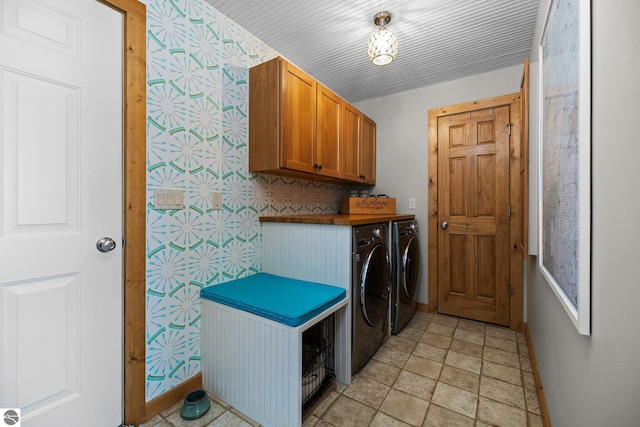 clothes washing area with washer and clothes dryer, cabinet space, wallpapered walls, and baseboards