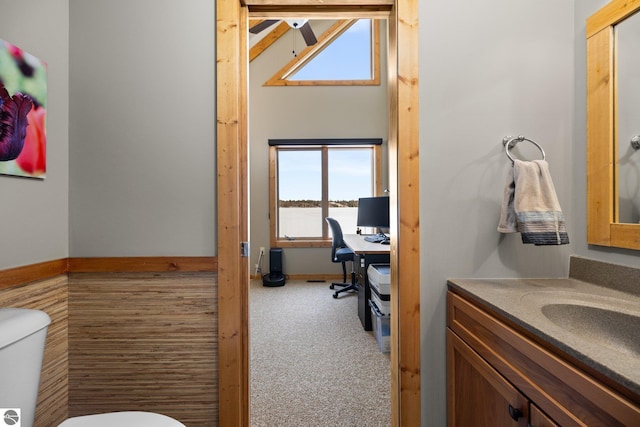 half bath with baseboards, toilet, a healthy amount of sunlight, and vanity