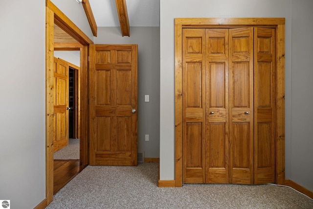 carpeted bedroom featuring beam ceiling and baseboards