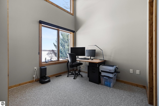 carpeted home office with a high ceiling and baseboards