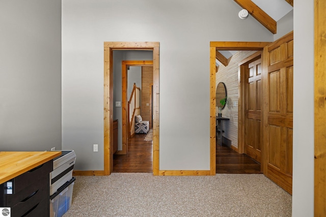 hallway featuring baseboards, vaulted ceiling with beams, and carpet