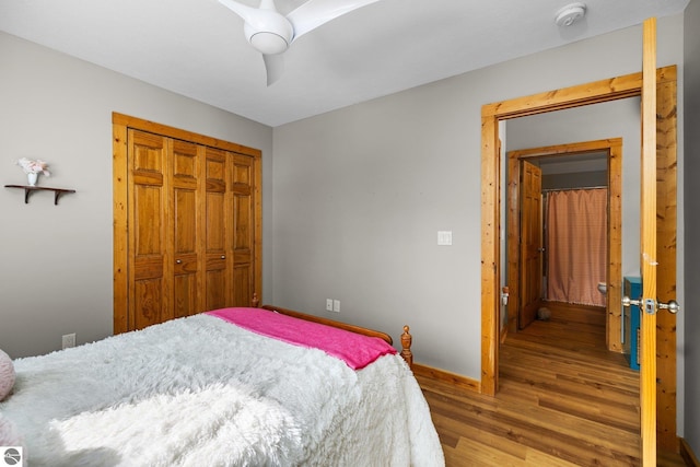 bedroom with a closet, ceiling fan, baseboards, and wood finished floors