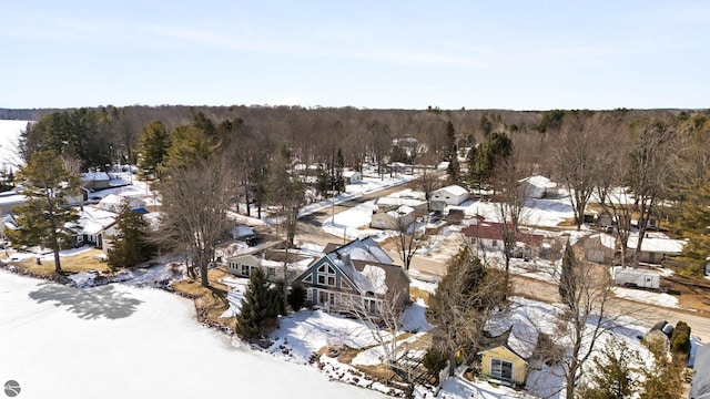 snowy aerial view featuring a wooded view and a residential view