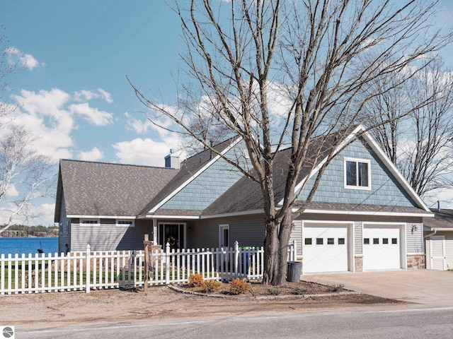 view of front of home with driveway, stone siding, fence private yard, and a garage