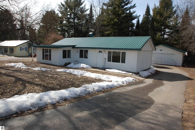 ranch-style home featuring an outdoor structure, a detached garage, and metal roof