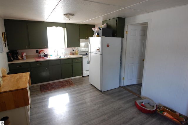 kitchen featuring green cabinetry, white appliances, wood finished floors, and a sink