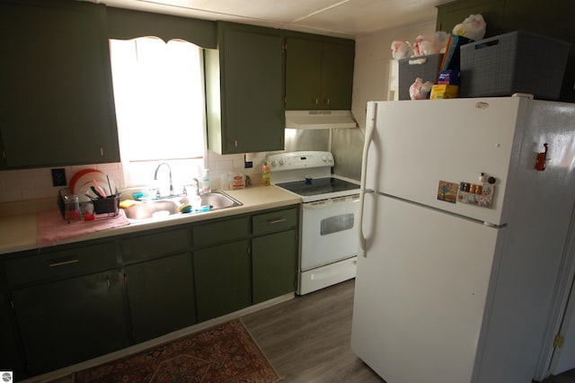 kitchen with white appliances, wood finished floors, a sink, decorative backsplash, and under cabinet range hood