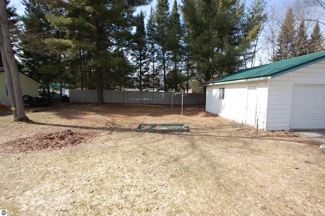 view of yard with an outdoor structure, a garage, and fence