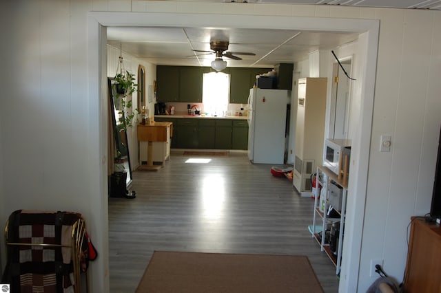 interior space with white appliances, wood finished floors, a ceiling fan, green cabinetry, and light countertops