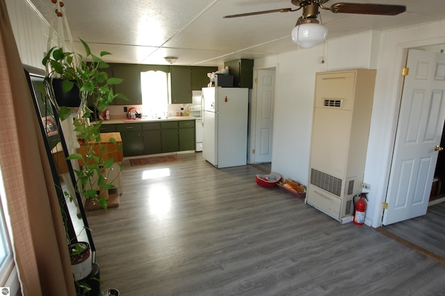 kitchen featuring green cabinetry, dark wood-style floors, a heating unit, and freestanding refrigerator