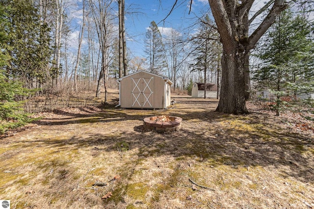 view of yard featuring a storage unit, a fire pit, and an outdoor structure