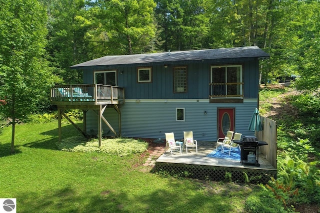 back of property featuring a yard, a wooded view, board and batten siding, and a deck