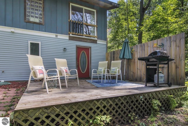 rear view of property with board and batten siding, a wooden deck, and fence