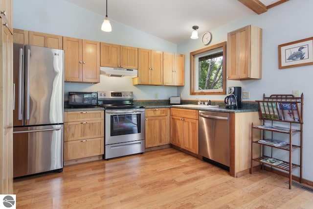 kitchen featuring under cabinet range hood, stainless steel appliances, dark countertops, and vaulted ceiling