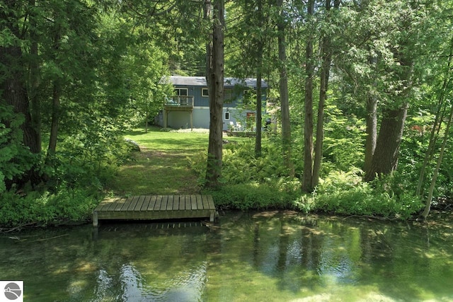 view of dock featuring a forest view and a water view