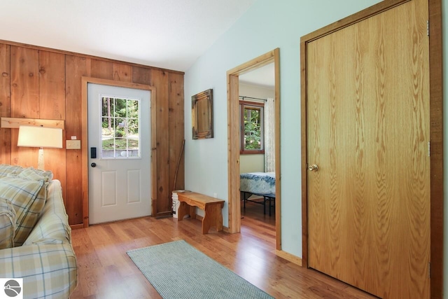 entryway with wooden walls, a healthy amount of sunlight, and light wood-style flooring