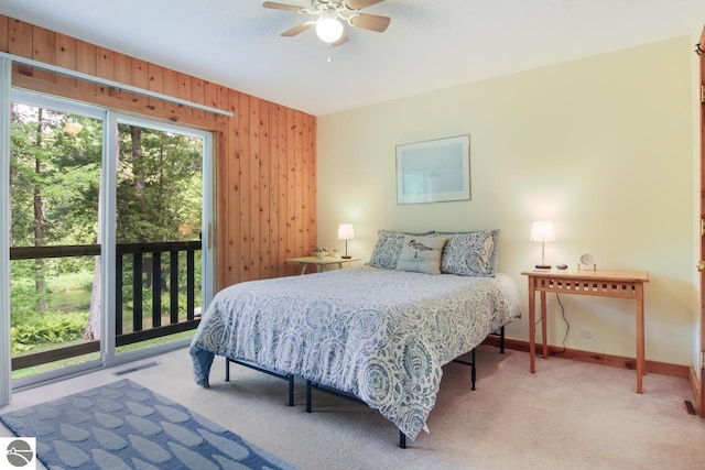 bedroom featuring visible vents, baseboards, carpet, wood walls, and access to outside