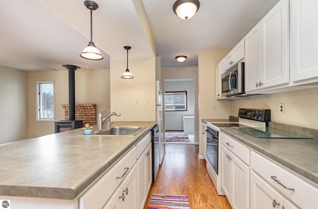 kitchen featuring range with electric cooktop, a sink, stainless steel microwave, black dishwasher, and light wood finished floors