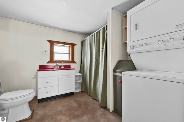 interior space featuring curtained shower, toilet, vanity, and stacked washer / dryer