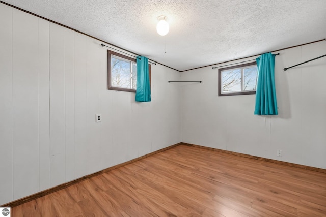 empty room with baseboards, light wood-style floors, and a textured ceiling