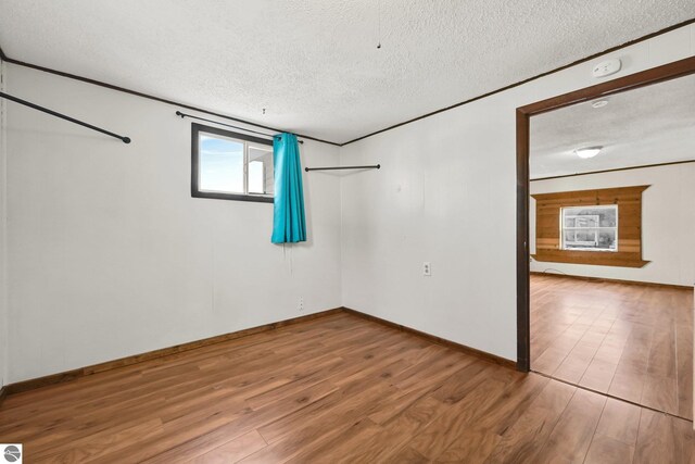 empty room with wood finished floors, baseboards, and a textured ceiling