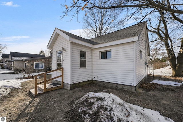 view of snowy exterior with roof with shingles