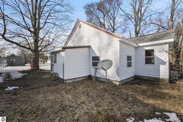 exterior space with roof with shingles and fence