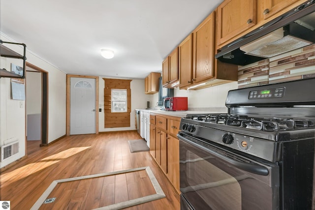 kitchen featuring black gas range oven, visible vents, light wood finished floors, under cabinet range hood, and light countertops