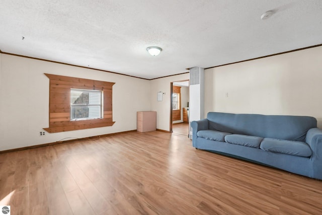 unfurnished living room featuring a textured ceiling, crown molding, baseboards, and wood finished floors