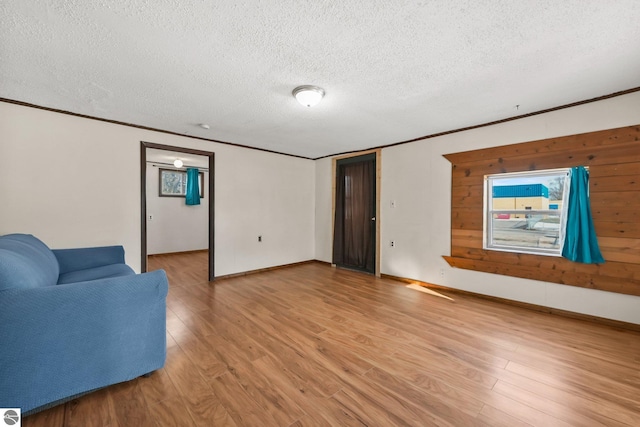 living area with a textured ceiling, light wood-type flooring, and ornamental molding