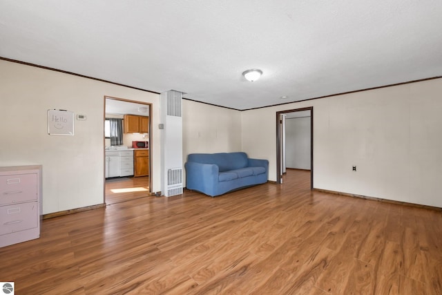 unfurnished room featuring light wood finished floors, crown molding, and baseboards