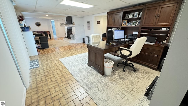 office area featuring a brick fireplace and a paneled ceiling