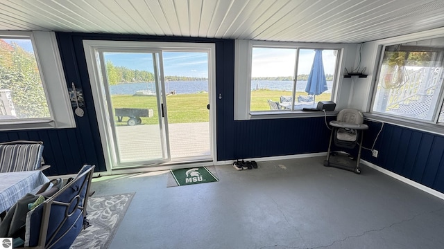 interior space featuring baseboards, a water view, and concrete floors