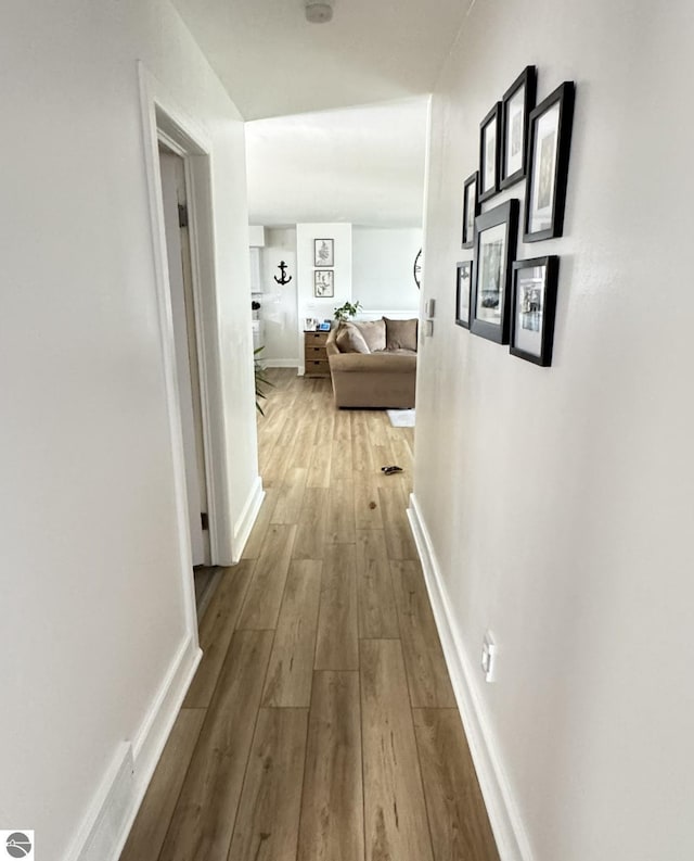 hallway featuring baseboards and hardwood / wood-style flooring