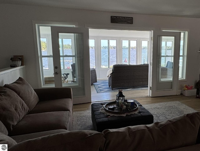 living room featuring french doors, a water view, and wood finished floors