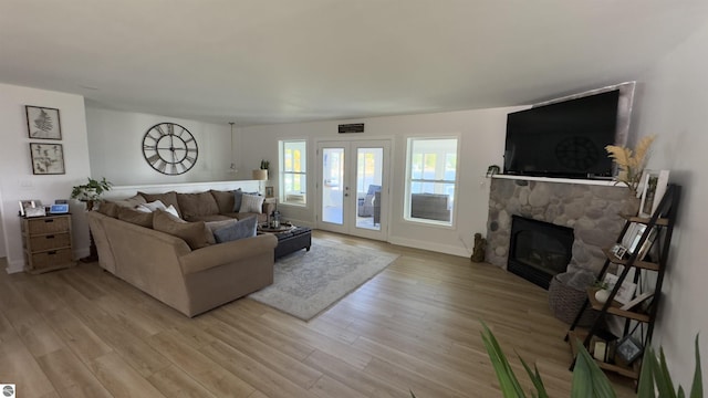 living area featuring a fireplace, visible vents, light wood finished floors, and baseboards