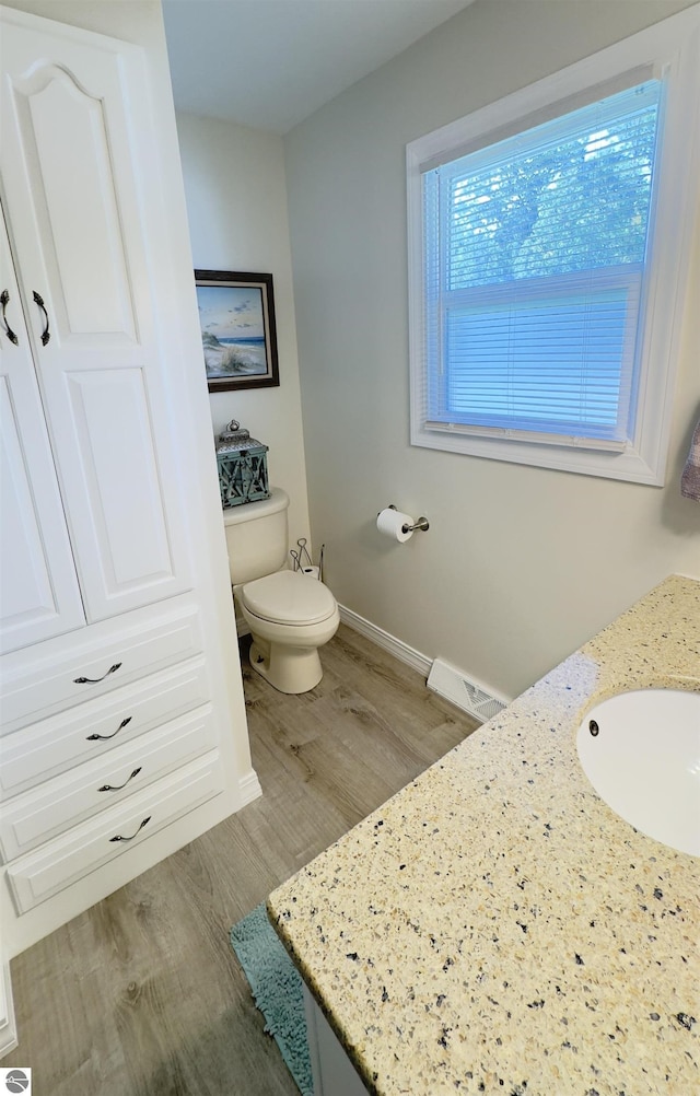 bathroom with visible vents, baseboards, toilet, wood finished floors, and vanity