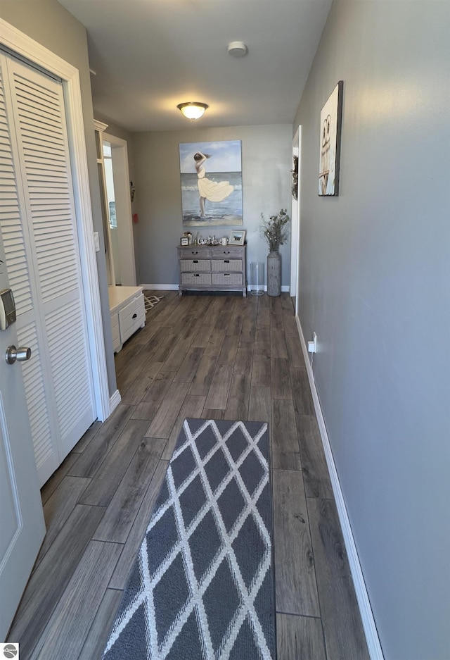 corridor featuring baseboards and dark wood-style flooring