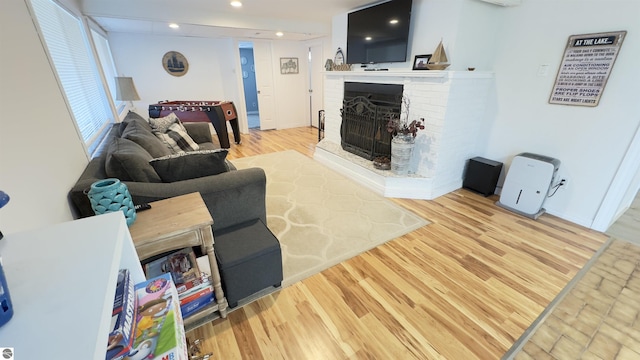 living area with a brick fireplace, recessed lighting, and wood finished floors