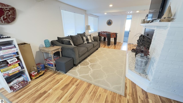 living area with recessed lighting, a brick fireplace, and light wood-style flooring