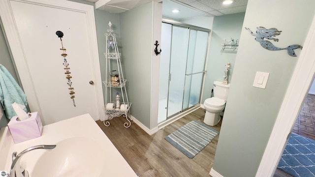 bathroom with a shower stall, toilet, wood finished floors, and recessed lighting