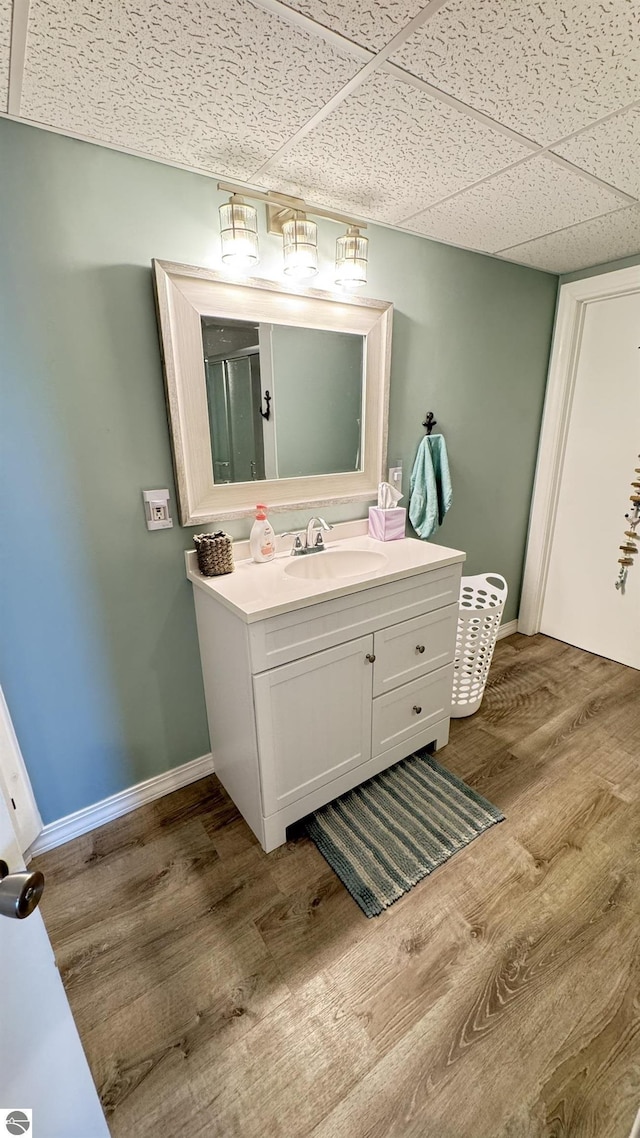 bathroom with a paneled ceiling, baseboards, and wood finished floors