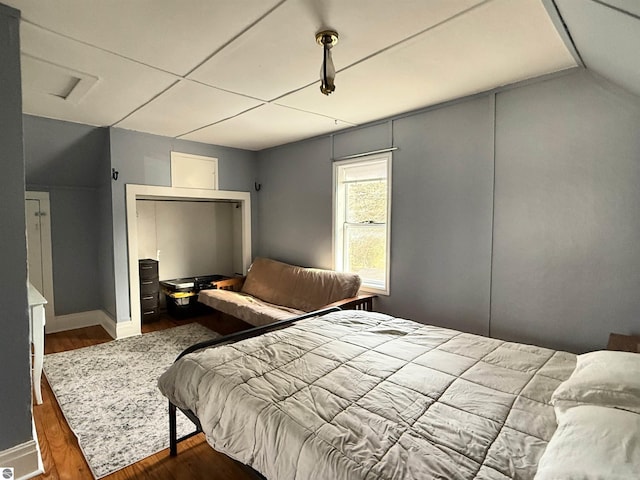 bedroom with baseboards, wood finished floors, and vaulted ceiling