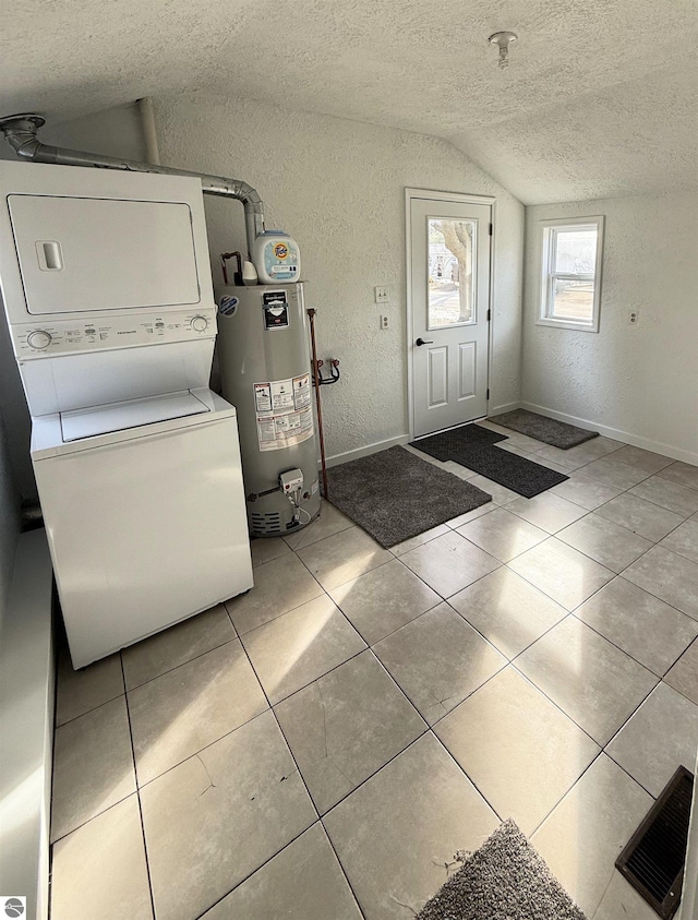 laundry area with gas water heater, a textured wall, a textured ceiling, and stacked washing maching and dryer